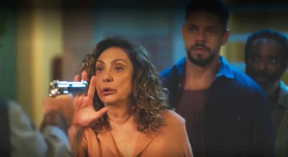 Agatha aparece colocando a mão na frente da arma que Antônio está apontando para Jonatas em cena de Terra e Paixão.