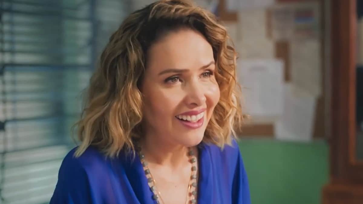 Gladys, expressando um olhar de felicidade, vestindo uma blusa azul e com um lindo sorrido no rosto em Terra e Paixão.