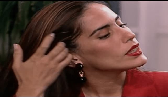 Na imagem, Ruth pegando no cabelo com a cara séria 