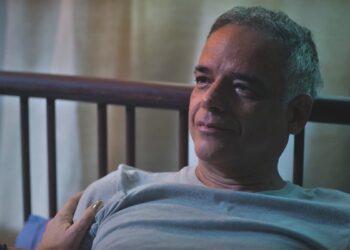 Andrade, personagem de Ângelo Antônio, com expressão de tristeza e com a cabeça encostada na cabeceira de uma cama, em Terra e Paixão.