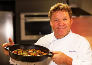 Claude Troigros segurando refeição e sorrindo para foto