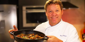 Claude Troigros segurando refeição e sorrindo para foto