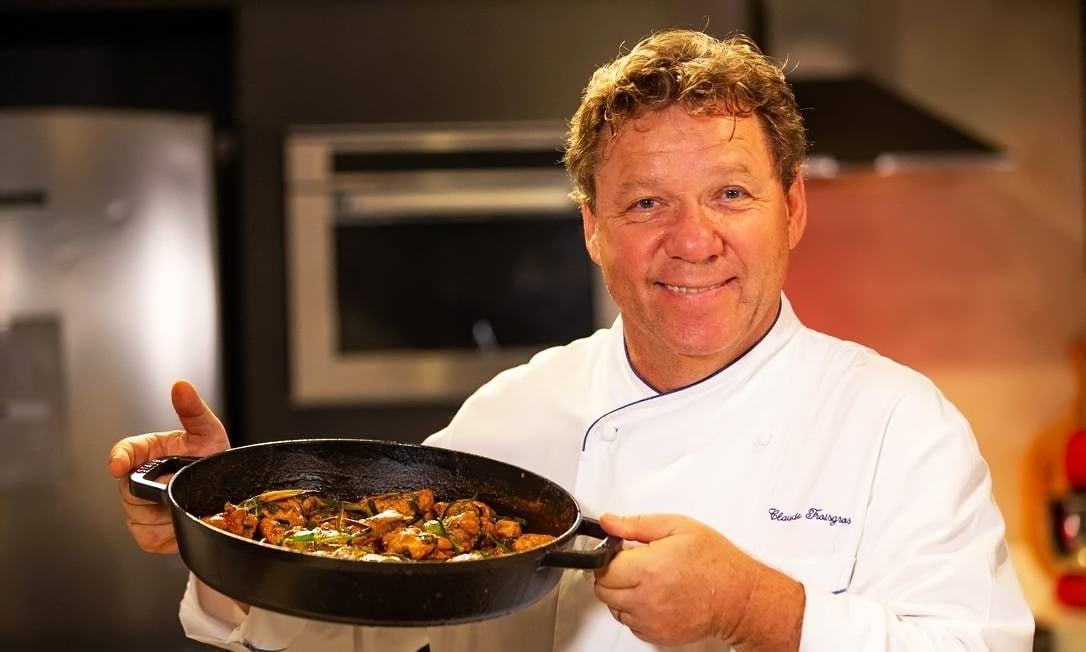 Claude Troigros segurando refeição e sorrindo para foto