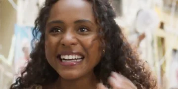 Beatriz, personagem de Duda Santos, sorrindo durante um bloco de rua em cena da novela Garota do Momento.