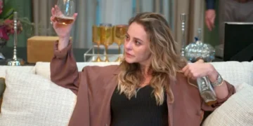 Heleninha, bêbada, segurando um copo de uísque na mão direita e uma garrafa da bebida na esquerda, em cena de Vale Tudo.