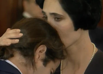 A Viagem: Em cena triste, Diná chega ao velório de Otávio e abraça os filhos dele com força para apoiá-los