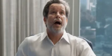 Ferette, veste uma camisa social branca e olha para cima com a boca aberta, em cena de Três Graças.