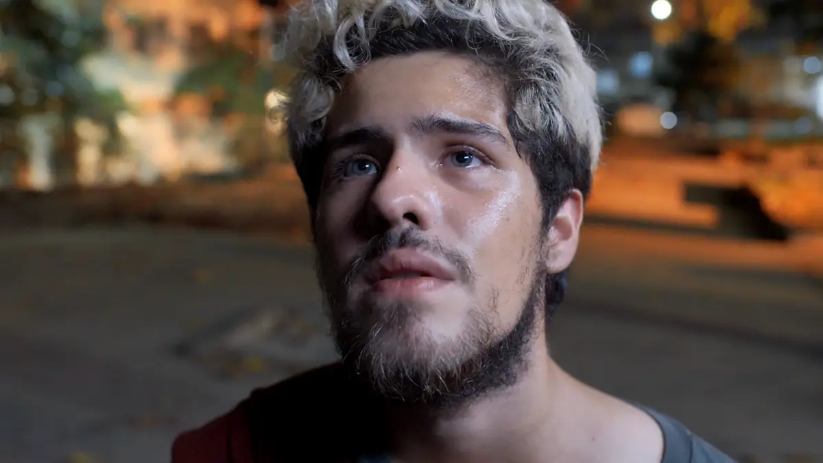 raul com olhar de tristeza, na rua durante a noite, em cena de Três Graças.