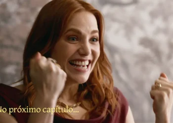 Adriana, mulher ruiva de cabelos ondulados, aparece sorrindo e comemorando com os punhos erguidos, usando blusa vinho e colar dourado. Na parte inferior esquerda, a imagem traz a frase “No próximo capítulo...” em letras amarelas.
