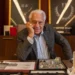 Arthur Brandão (Antonio Fagundes), da novela Quem Ama Cuida, aparece sorridente em seu escritório, sentado atrás de uma mesa com joias e pedras preciosas expostas, tendo ao fundo vitrines com colares luxuosos.